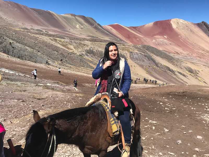 Mulher de cavalo sentido a montanha colorida